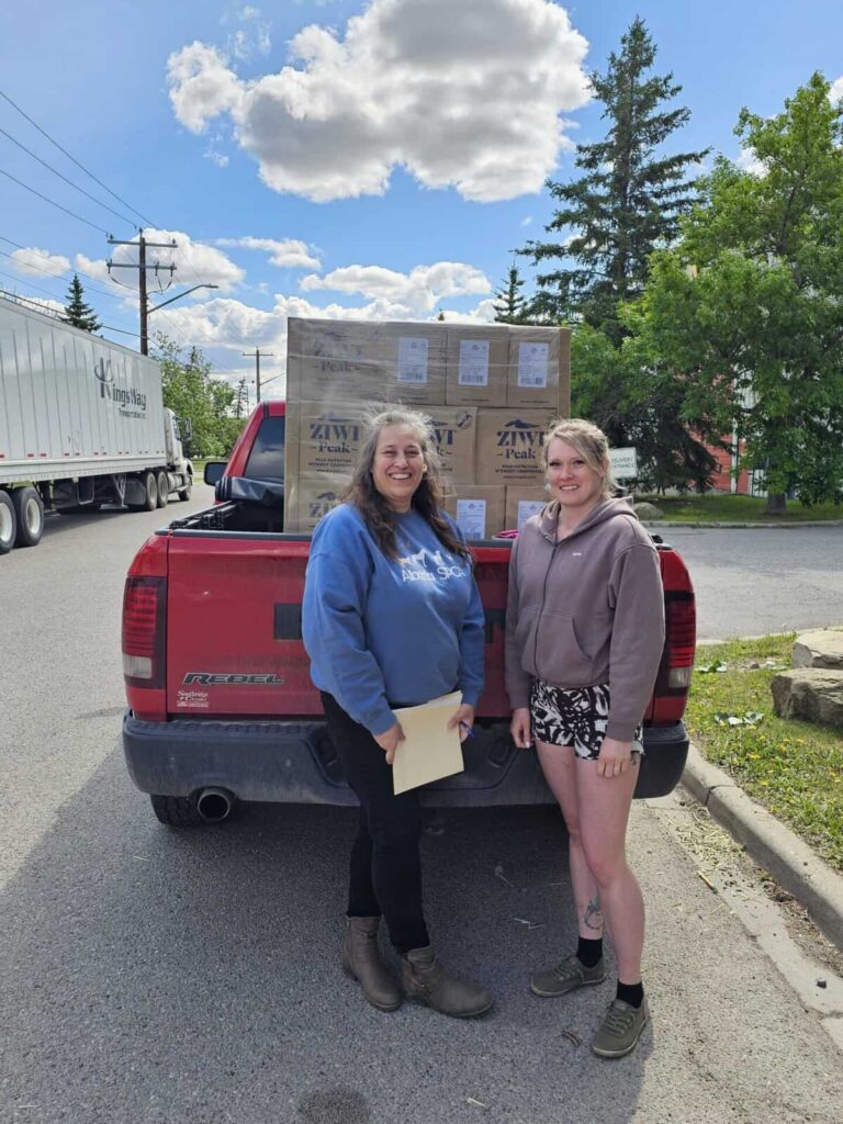 Ziwi pet food donation pallets in the back of a truck with Alberta SPCA staff smiling and celebrating the donation.