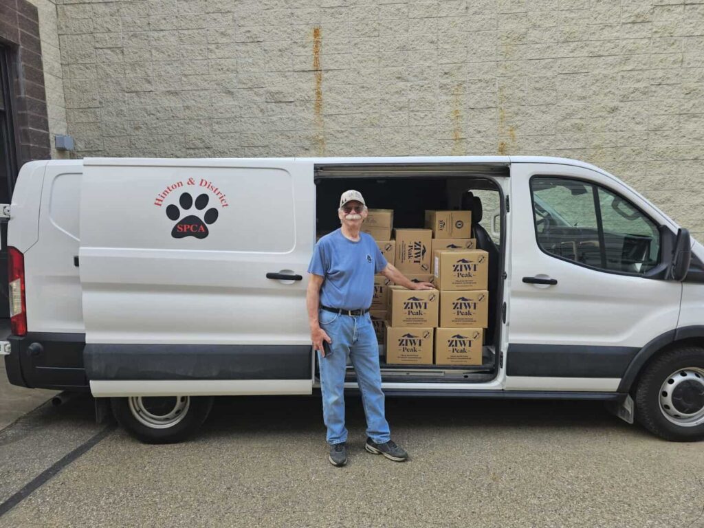 Ziwi pet food donation pallets in the back of a van with man smiling and celebrating the donation.