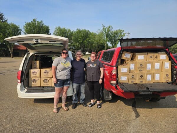 Ziwi pet food donation pallets in the back of cars trucks with peoplef smiling and celebrating the donation.